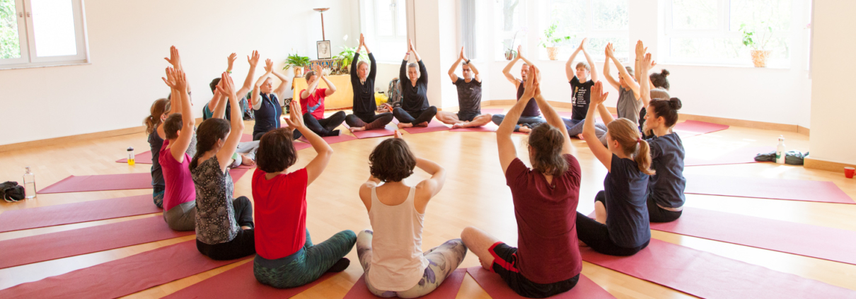 Yogaschüler sitzen im Kreis mit den Händen nach oben am Leipziger Yogatag